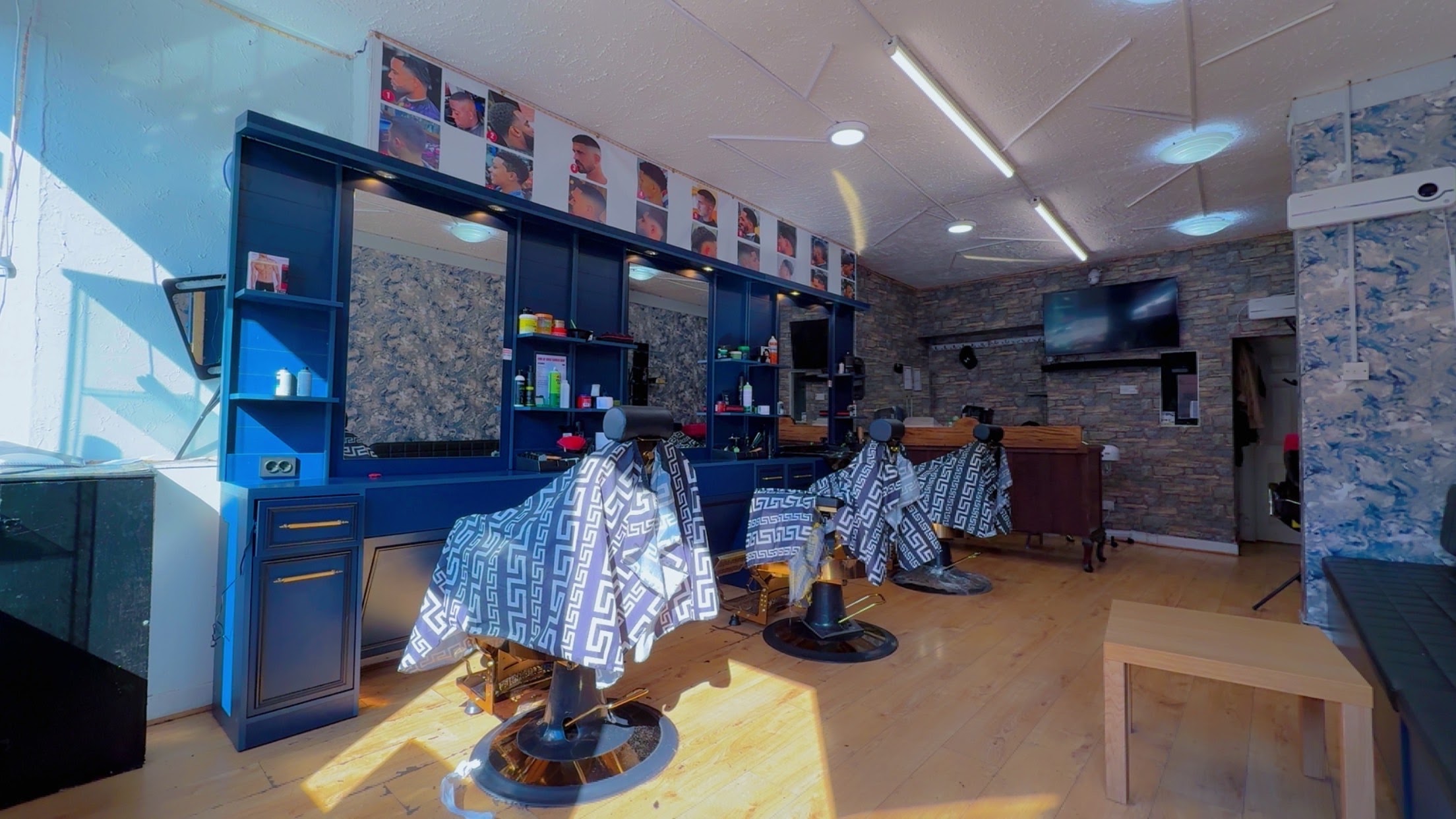 Inside Gadaa Barber Shop — navy stations with gold detailing and three barber chairs